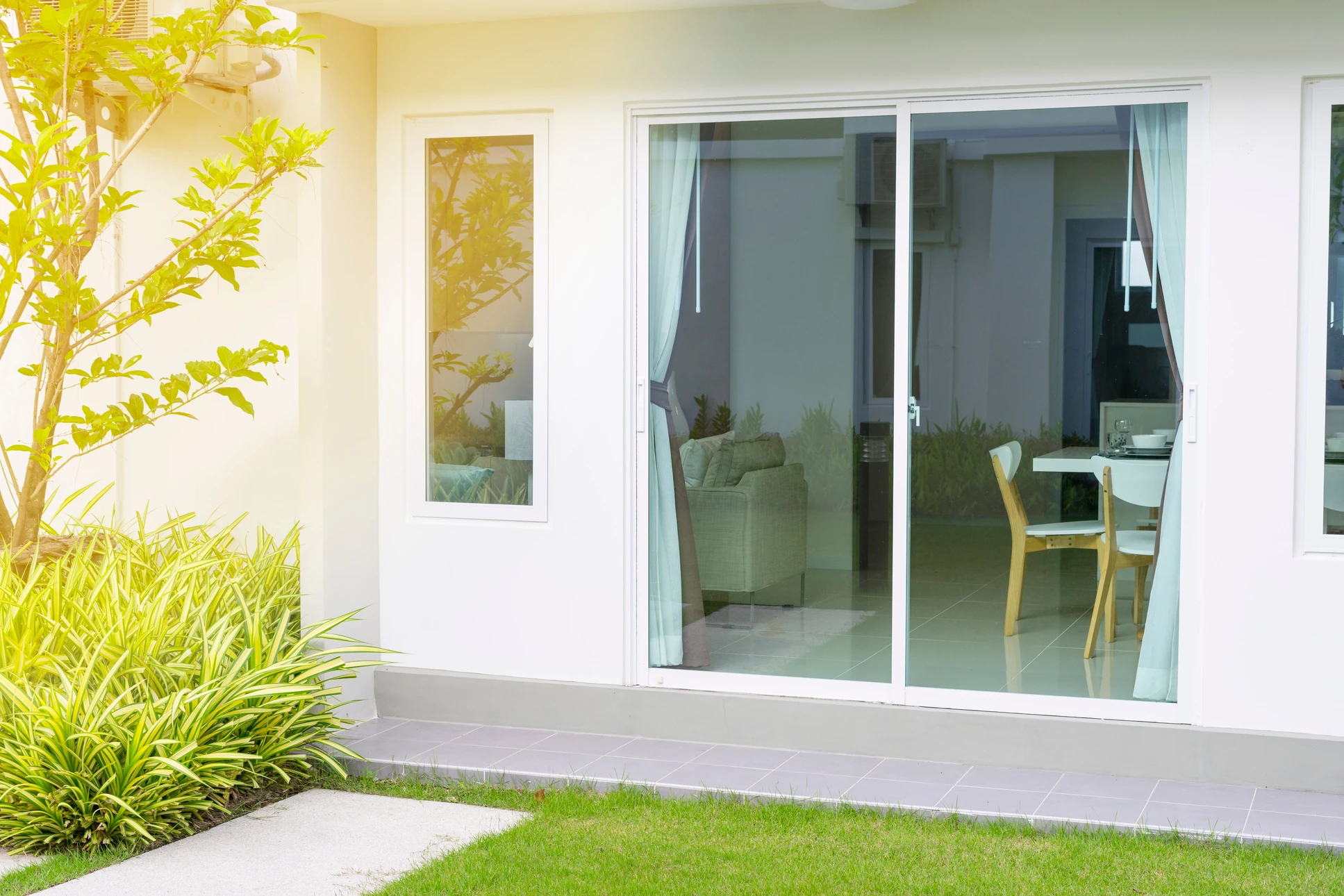 Façade moderne d'habitation avec baie vitrée coulissante ouverte donnant sur salon lumineux