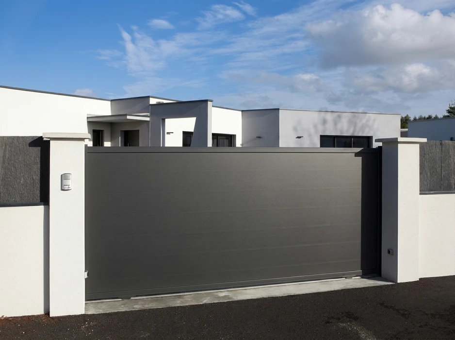 Portail coulissant aluminium gris anthracite, lames horizontales, motorisé, installé entre deux piliers en béton enduit blanc