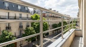 Garde-corps sur mesure en acier inoxydable poli avec barreaudage horizontal moderne, installé sur une terrasse ou balcon résidentiel. La photo montre le détail du garde-corps en gros plan, mettant en évidence la qualité de la finition, les barreaux horizontaux espacés régulièrement, et la main courante. L'arrière-plan flou révèle un environnement urbain ou résidentiel type Île-de-France. Lumière naturelle, photo de qualité professionnelle.